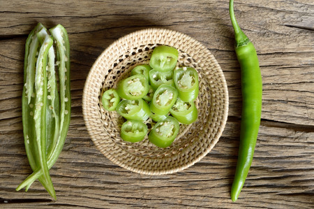 green pepper in wicker basket on wooden backgroundの写真素材