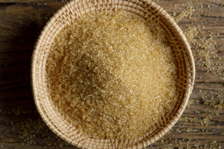 brown sugar in wicker basket on wooden backgroundの写真素材