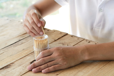 woman pick wooden toothpick from plastic box on wood table, for cleaning teethの写真素材