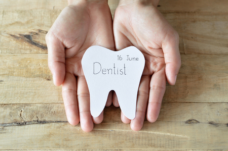 dentist appointment, paper cuts tooth shape write the word that dentist and date in woman handの写真素材