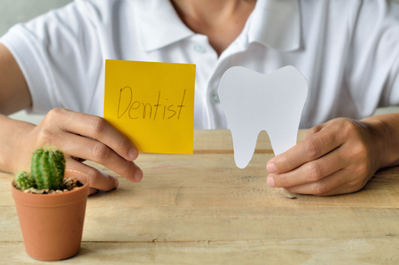 woman hold paper cuts tooth shape and write the word that dentist, dental conceptの写真素材