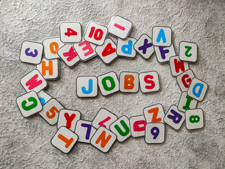Colorful magnetic plastics with text "JOBS" around the alphabet on gray textured background. Selective focus imageの写真素材