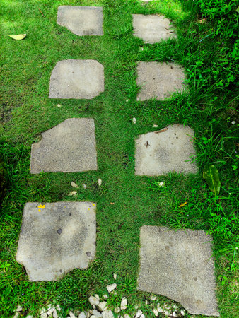 Landscaping of garden footpath from natural rough stone with green lawn around, nobodyの写真素材