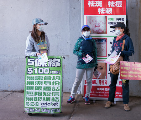 Flushing, New York - June 03 2015: Three girls wearing masks advertising different services in the street.のeditorial素材