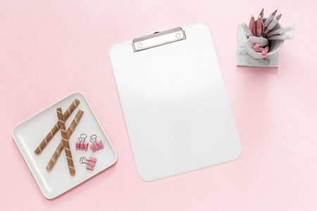 Desktop flat lay of office stationery items and blank clipboard on pink desktopの写真素材