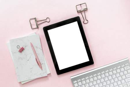 Desktop flat lay of office stationery items and blank tablet on pink backgroundの写真素材