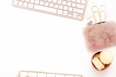Feminine desktop with gold and pink stationery including a keyboard and mouseの写真素材