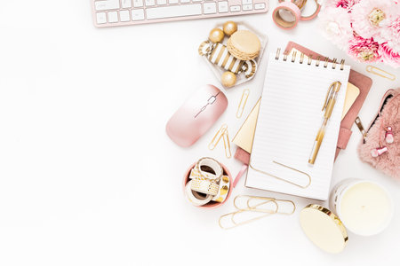 Feminine desktop with gold and pink stationery including a keyboard and mouseの写真素材