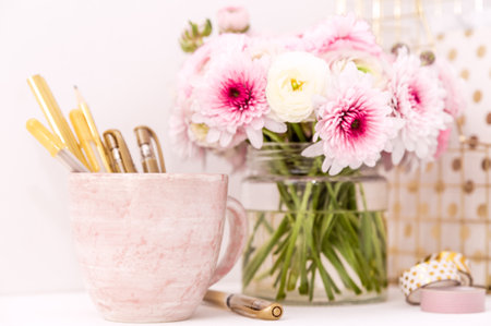 Feminine desktop with gold and pink stationery including fresh flowersの写真素材