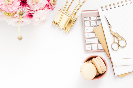 Feminine desktop with gold and pink stationery including a keyboard and mouseの写真素材