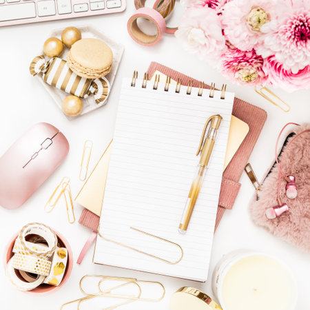 Feminine desktop with gold and pink stationery including a keyboard and mouseの写真素材