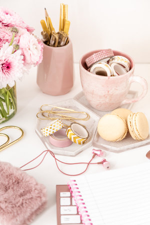 Feminine desktop with gold and pink stationery including fresh flowersの写真素材