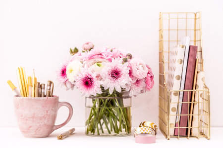 Feminine desktop with gold and pink stationery including fresh flowersの写真素材