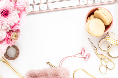 Feminine desktop with gold and pink stationery including a keyboard and mouseの写真素材