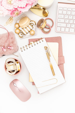 Feminine desktop with gold and pink stationery including a keyboard and mouseの写真素材