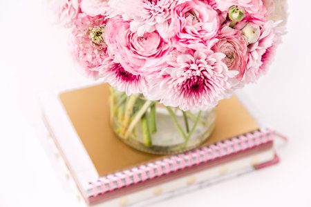 Feminine desktop with gold and pink stationery including fresh flowersの写真素材