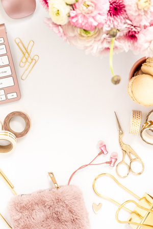 Feminine desktop with gold and pink stationery including a keyboard and mouseの写真素材