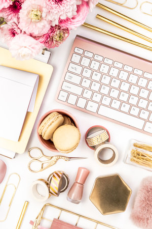 Feminine desktop with gold and pink stationery including a keyboard and mouseの写真素材