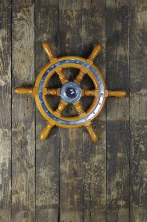 steering wheel of sailing-ship on a board backgroundの写真素材