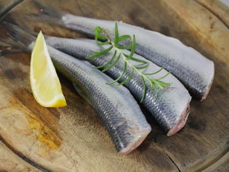 three herrings with lemon on a chopping boardの写真素材