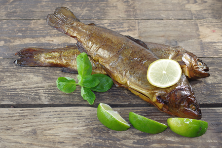 two smoked trout with lemon on wooden backgroundの写真素材