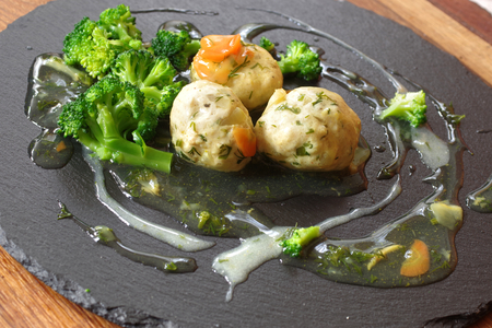 forcemeat balls with sauce and vegetable on black stoneの写真素材