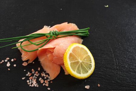 slices of smoked salmon with dill black plate backgroundの写真素材