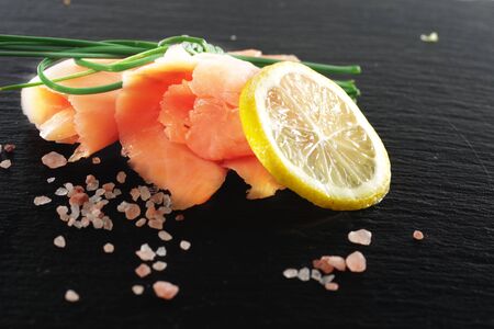 slices of smoked salmon with dill black plate backgroundの写真素材
