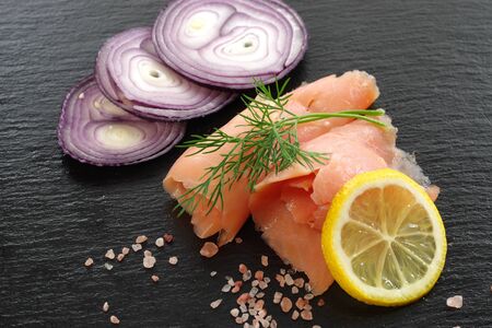 slices of smoked salmon with dill black plate backgroundの写真素材