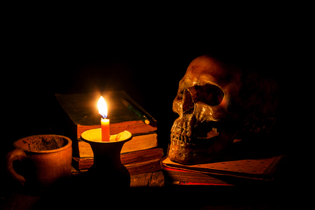 Skull and candle with candlestick on wooden background, still life conceptの写真素材