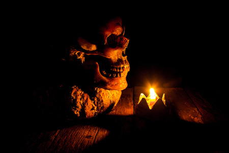 Skull and candle with candlestick on wooden background, still life conceptの写真素材