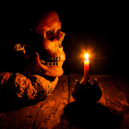 Skull and candle with candlestick on wooden background, still life conceptの写真素材