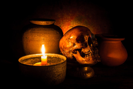 Skull and candle with candlelight on wooden background, still life conceptの写真素材