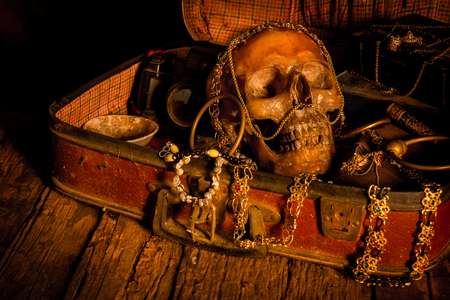 Still life with human skull with old treasure chest and gold, diamond and jewelry on wooden backgroundの写真素材