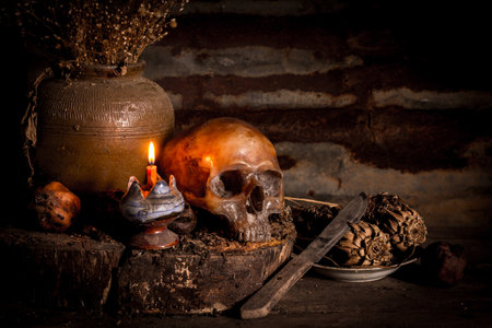 Human skull and candle with on wooden floor and old dirty wall background, and vase flower,and glass,and bottle of wine, still life conceptの写真素材