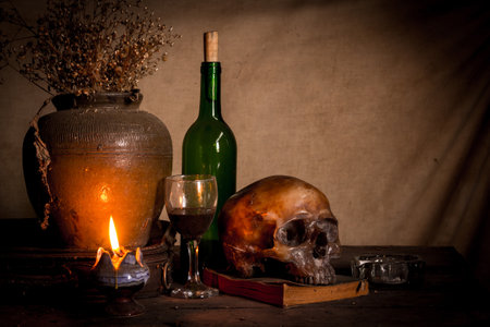 Human skull and candle with on wooden floor and old dirty wall background, and vase flower,and glass,and bottle of wine, still life conceptの写真素材