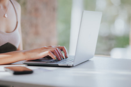 Close up of businesswoman hands typing on laptop computer in office.