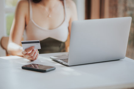 Closeup of woman holding credit card and using laptop for online shoppingの写真素材