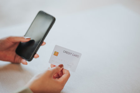 Close-up of female hands holding credit card and using smartphone. Online shopping concept