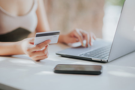 Close up of woman hand holding credit card and using laptop computer. Online shopping concept.の写真素材