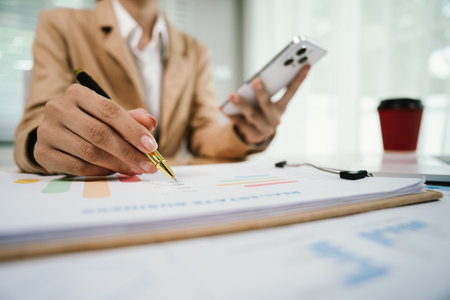 Businesswoman analyzing investment charts with smartphone. Accounting,investment concept.の写真素材