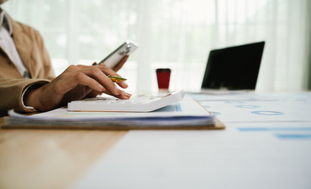 Businessman analyzing investment charts with calculator and laptop computer in office. Accountingの写真素材