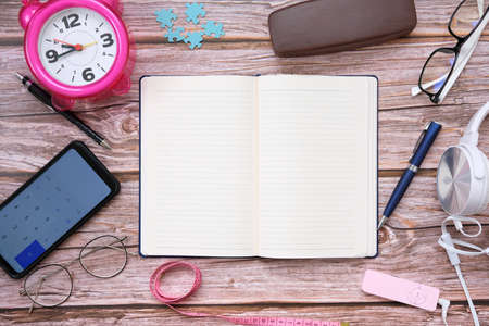 Notebook paper and mobile phone on wood table background and space for textの写真素材