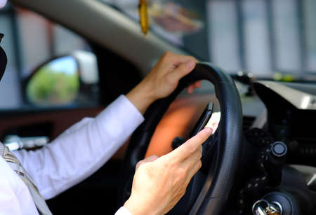Close-up of a woman using a smartphone while driving a car