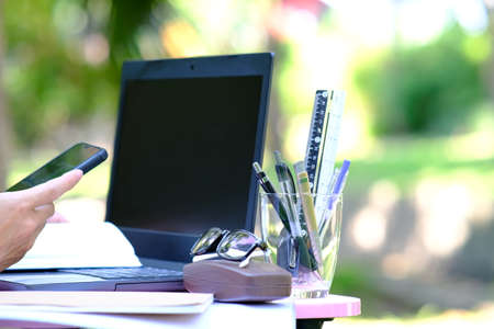 Close-up of a businesswoman using a mobile phone while working on a laptop outdoors