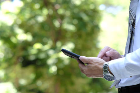 Businessman using smart phone in the park. Business and technology concept.の写真素材