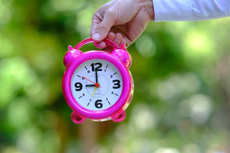 Businessman hand holding alarm clock and space