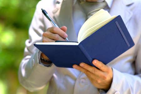 Close-up of a man in a white coat with a book in his hands