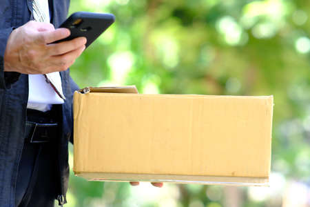 Man holding parcel box and using smart phone. Online shopping concept.
