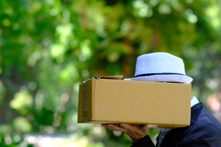 A man in a hat is holding a cardboard box in his hand.